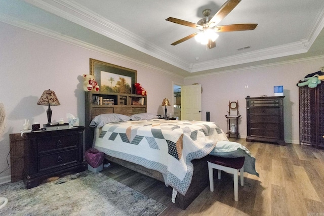 bedroom featuring crown molding, a tray ceiling, ceiling fan, and light hardwood / wood-style flooring