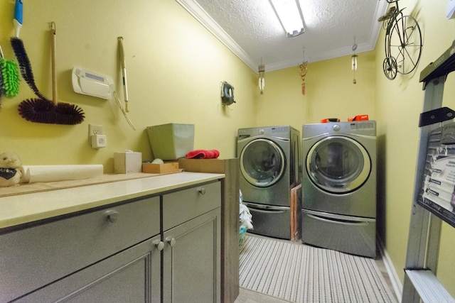 washroom with crown molding, a textured ceiling, cabinets, and washing machine and clothes dryer