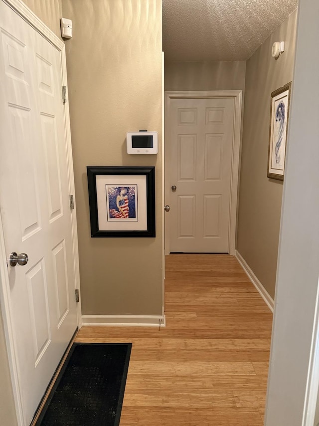 hall featuring a textured ceiling and light wood-type flooring