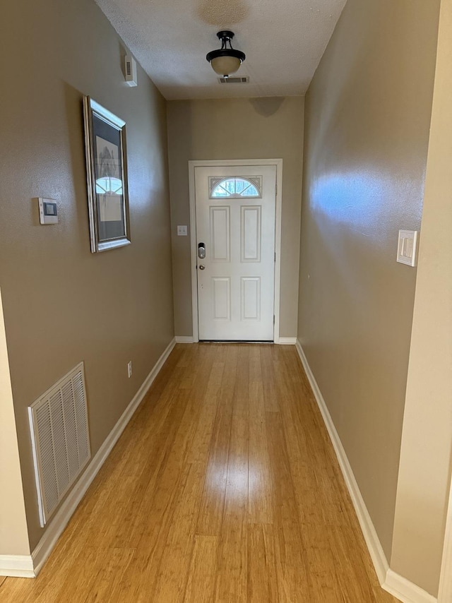 doorway to outside featuring a textured ceiling and light wood-type flooring