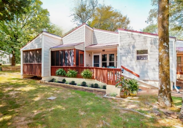 rear view of property with a lawn, a sunroom, and a deck