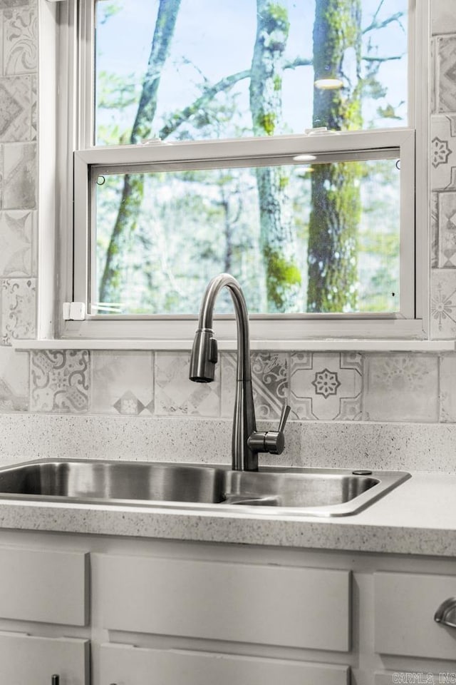 interior details featuring white cabinetry, sink, and decorative backsplash