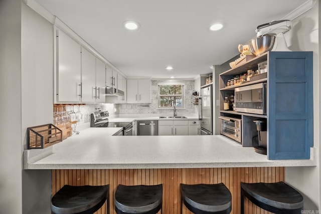 kitchen featuring white cabinetry, a kitchen bar, kitchen peninsula, and appliances with stainless steel finishes