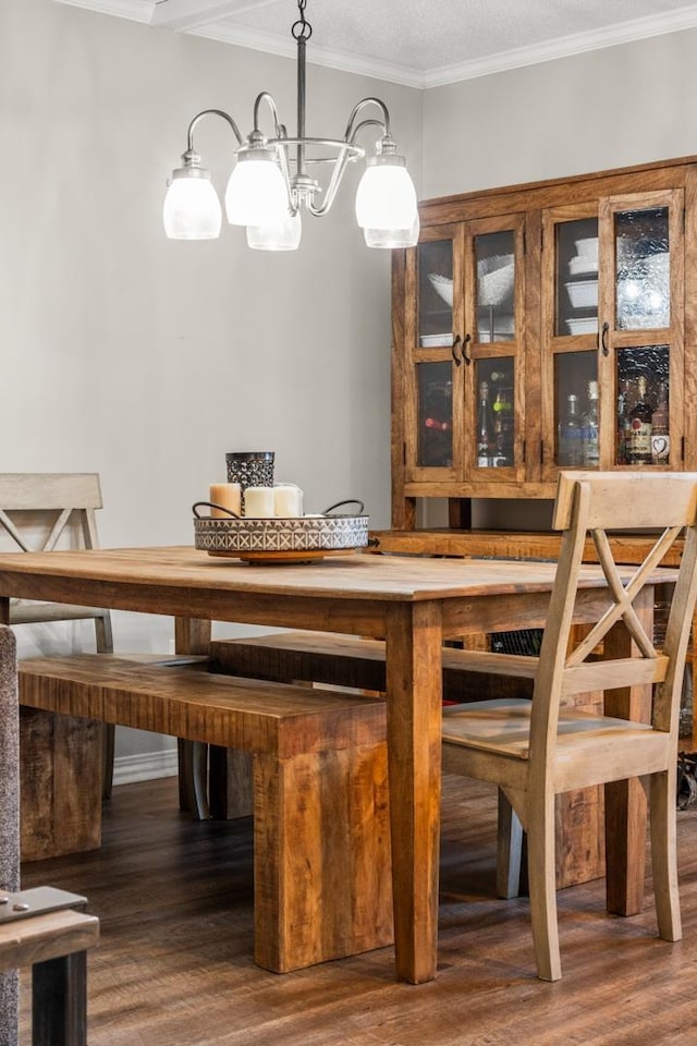 dining space featuring wood-type flooring, ornamental molding, and an inviting chandelier