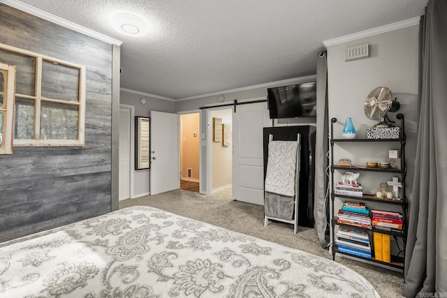 bedroom featuring ornamental molding, a barn door, carpet floors, and a textured ceiling