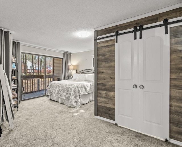 bedroom with a barn door, carpet floors, access to outside, and a textured ceiling