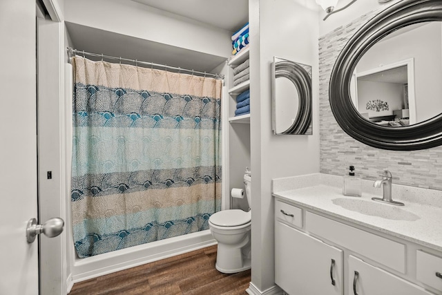 bathroom with hardwood / wood-style flooring, backsplash, a shower with shower curtain, vanity, and toilet