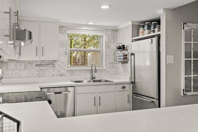 kitchen with tasteful backsplash, appliances with stainless steel finishes, sink, and white cabinets