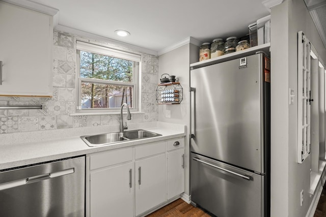 kitchen featuring white cabinetry, sink, backsplash, ornamental molding, and stainless steel appliances