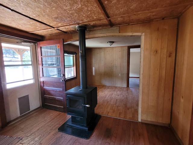 doorway featuring hardwood / wood-style flooring, wood walls, and a wood stove