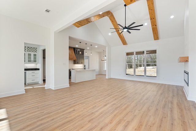 unfurnished living room featuring ceiling fan, beam ceiling, high vaulted ceiling, and light hardwood / wood-style flooring