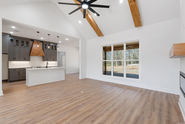 unfurnished living room with high vaulted ceiling, sink, ceiling fan, and light hardwood / wood-style floors