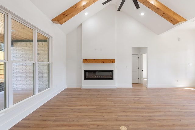 unfurnished living room featuring ceiling fan, high vaulted ceiling, beamed ceiling, and light wood-type flooring