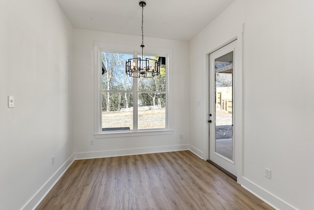 unfurnished dining area featuring a chandelier and light hardwood / wood-style flooring