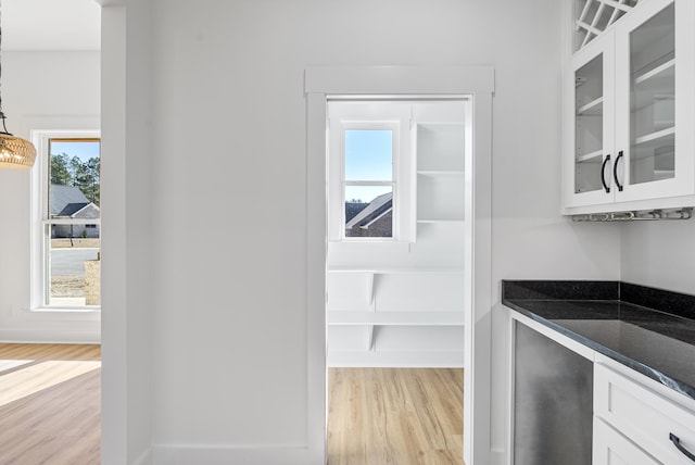 interior space with white cabinetry, hanging light fixtures, light hardwood / wood-style flooring, and a healthy amount of sunlight