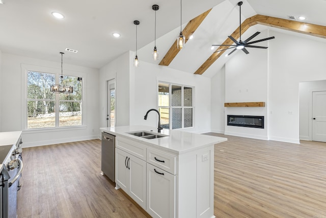 kitchen featuring sink, hanging light fixtures, stainless steel appliances, an island with sink, and white cabinets