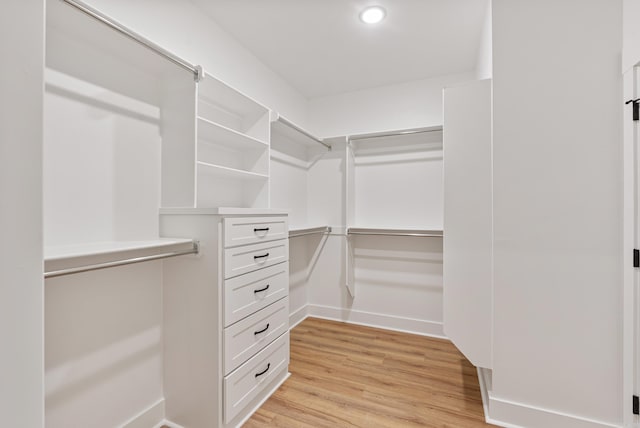 walk in closet with light hardwood / wood-style floors