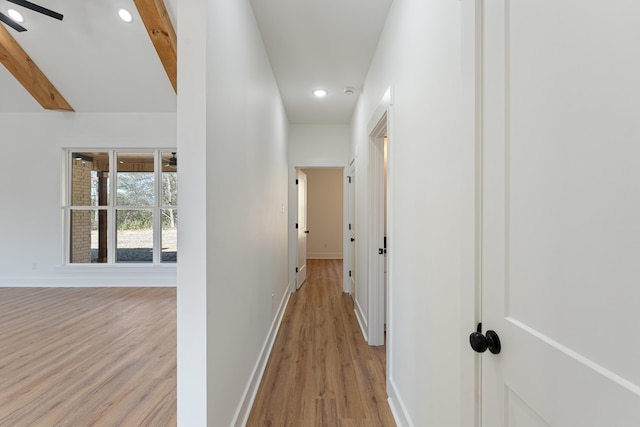 corridor with beam ceiling and light hardwood / wood-style flooring