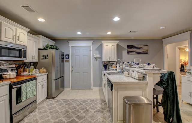 kitchen with sink, crown molding, light tile patterned floors, stainless steel appliances, and white cabinets