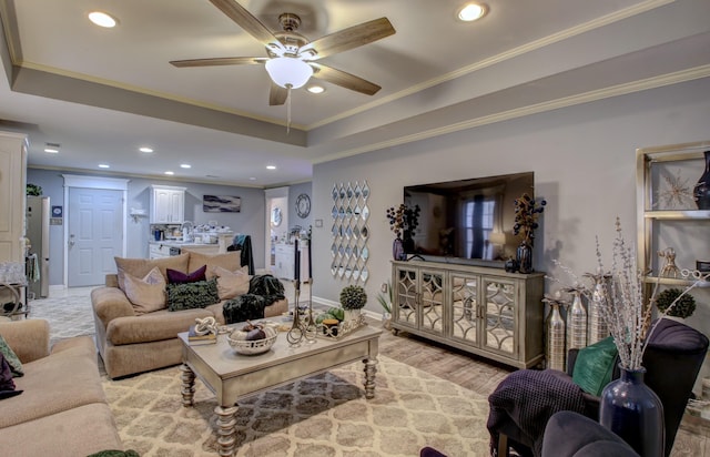 living room with ornamental molding, a raised ceiling, and light hardwood / wood-style flooring