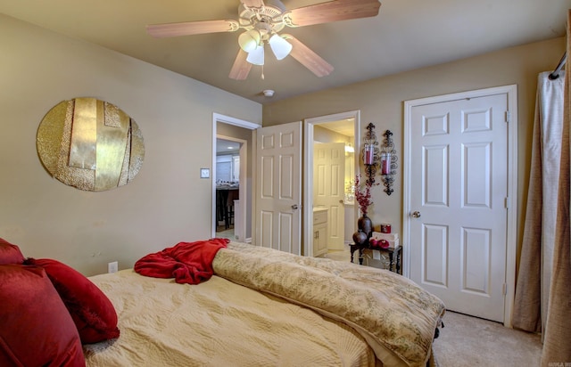 carpeted bedroom with ensuite bath and ceiling fan