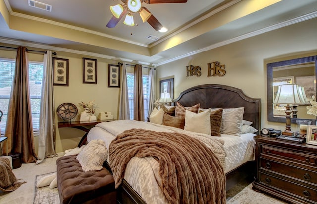 carpeted bedroom with ornamental molding, ceiling fan, and a tray ceiling