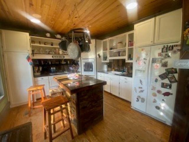 205 S Main, Okolona, AR 71962 - kitchen with wooden ceiling, white refrigerator, a kitchen island, hardwood / wood-style flooring, and white cabinets