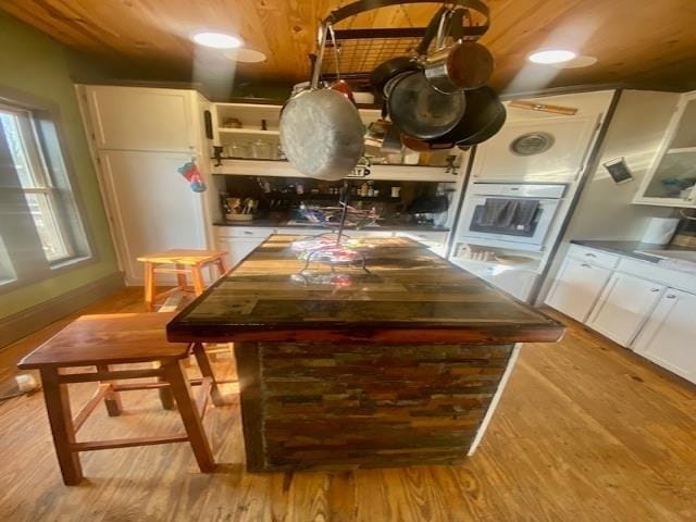 205 S Main, Okolona, AR 71962 - kitchen featuring oven, light wood-type flooring, a kitchen island, and white cabinets