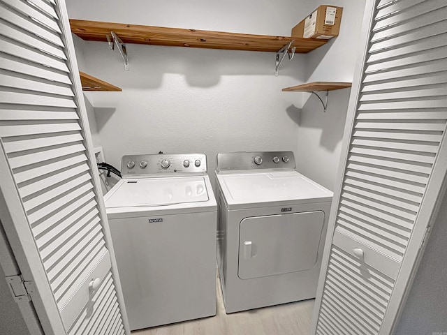 laundry room featuring washing machine and dryer and light hardwood / wood-style flooring