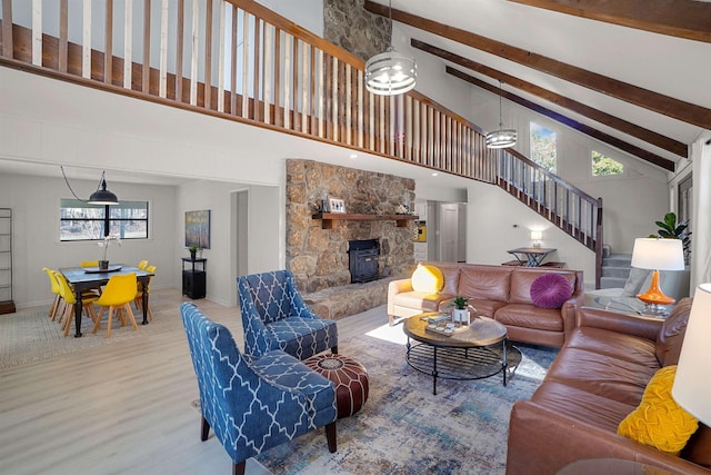 living room with beam ceiling, a high ceiling, and light wood-type flooring