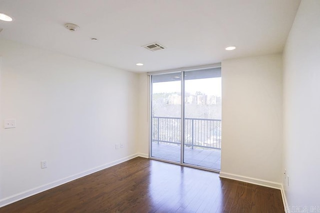 spare room featuring dark wood-type flooring and a wall of windows