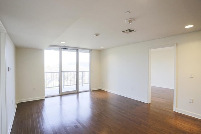 spare room with dark hardwood / wood-style flooring and a wall of windows