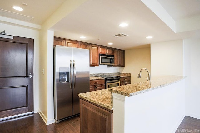 kitchen with sink, appliances with stainless steel finishes, dark hardwood / wood-style floors, kitchen peninsula, and light stone countertops