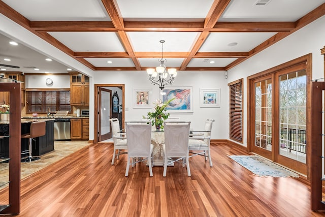 dining space with coffered ceiling, beam ceiling, a chandelier, and light wood-type flooring