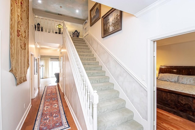 staircase featuring wood-type flooring and ornamental molding