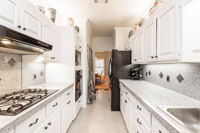 kitchen featuring light tile patterned flooring, stainless steel gas cooktop, white cabinetry, ornamental molding, and oven