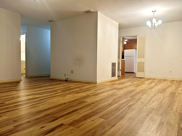 empty room with an inviting chandelier and light hardwood / wood-style floors