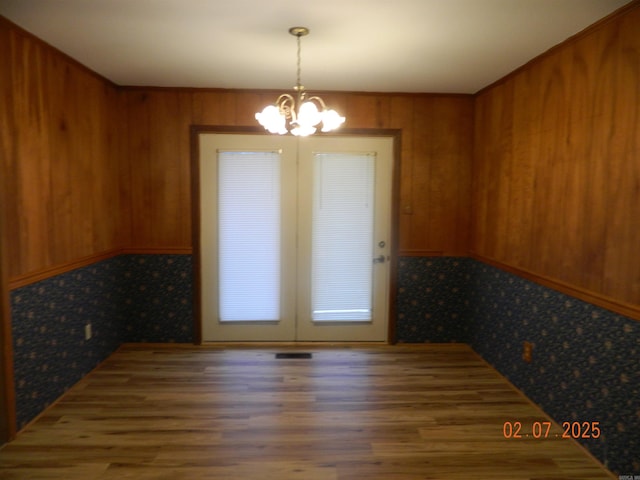 unfurnished dining area with a chandelier and wooden walls