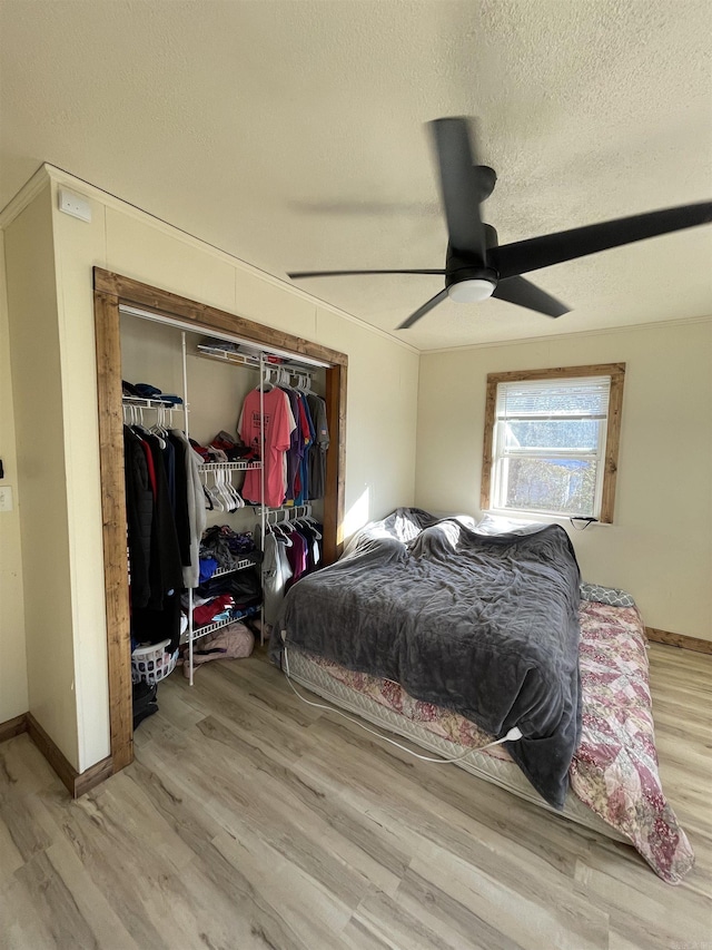 bedroom featuring ceiling fan, a textured ceiling, light hardwood / wood-style floors, and a closet