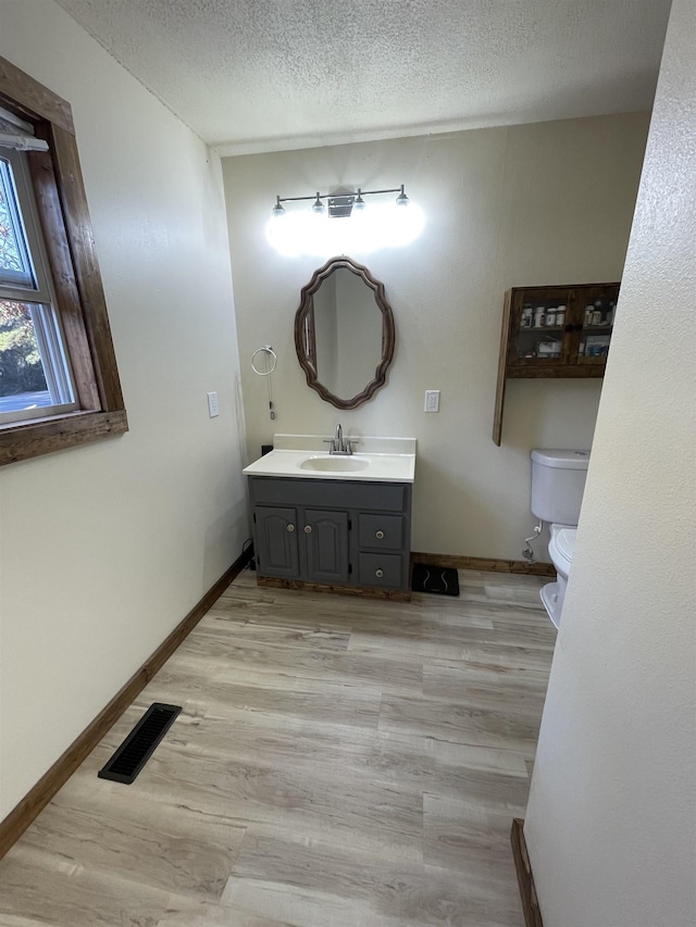 bathroom with wood-type flooring, vanity, a textured ceiling, and toilet