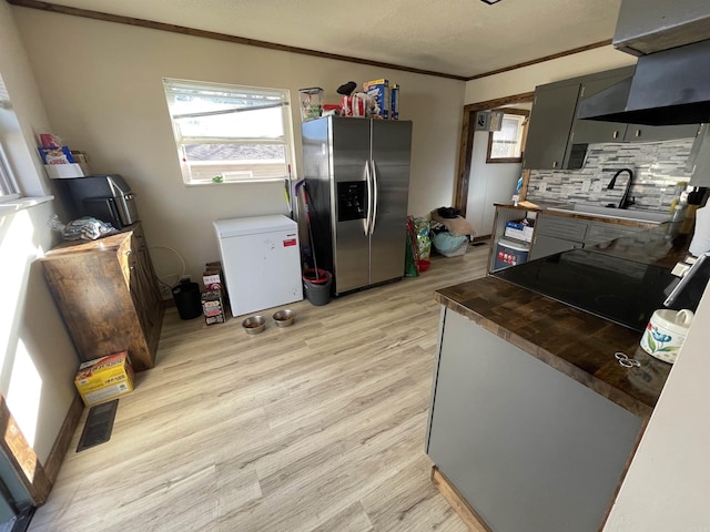 kitchen with tasteful backsplash, sink, ornamental molding, light hardwood / wood-style floors, and stainless steel refrigerator with ice dispenser