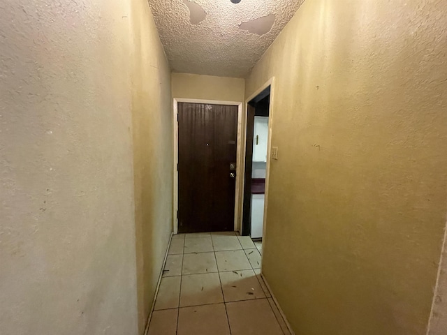 hall featuring light tile patterned floors and a textured ceiling