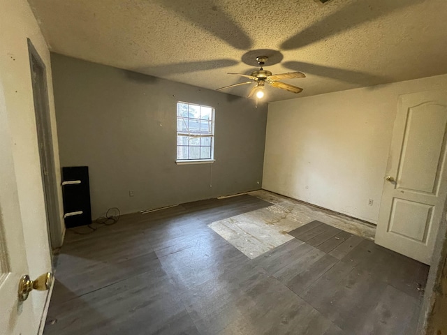 empty room with ceiling fan, dark hardwood / wood-style floors, and a textured ceiling