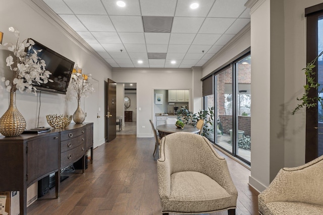 interior space featuring a drop ceiling, dark wood-type flooring, and ornamental molding