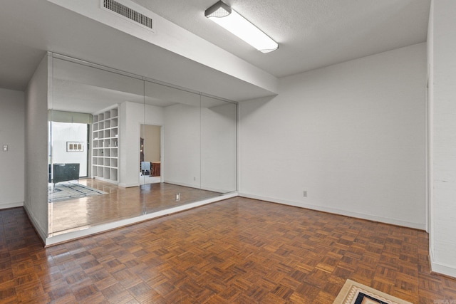 basement featuring dark parquet flooring and a textured ceiling