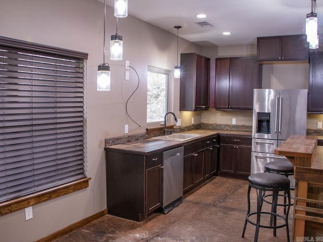 kitchen featuring pendant lighting, sink, stainless steel appliances, and dark brown cabinetry