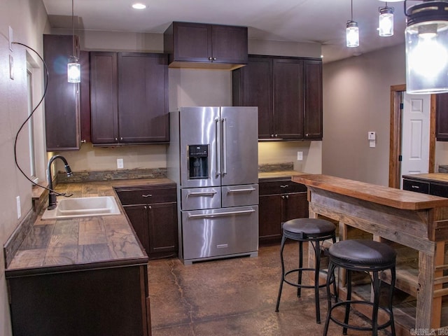 kitchen with high end fridge, sink, pendant lighting, and dark brown cabinets