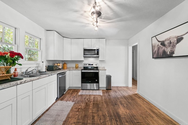 kitchen with stainless steel appliances, sink, white cabinets, and dark hardwood / wood-style flooring