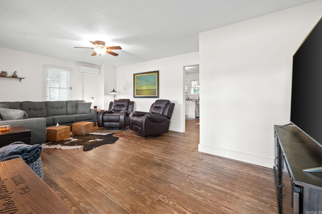 living room featuring a healthy amount of sunlight, dark hardwood / wood-style flooring, and a wall unit AC