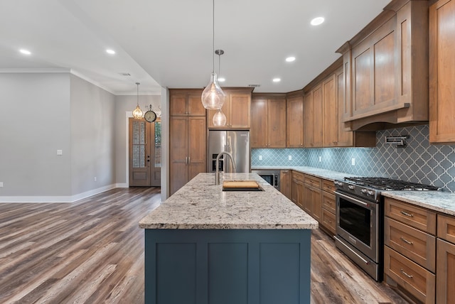 kitchen with appliances with stainless steel finishes, pendant lighting, sink, light stone countertops, and a center island with sink